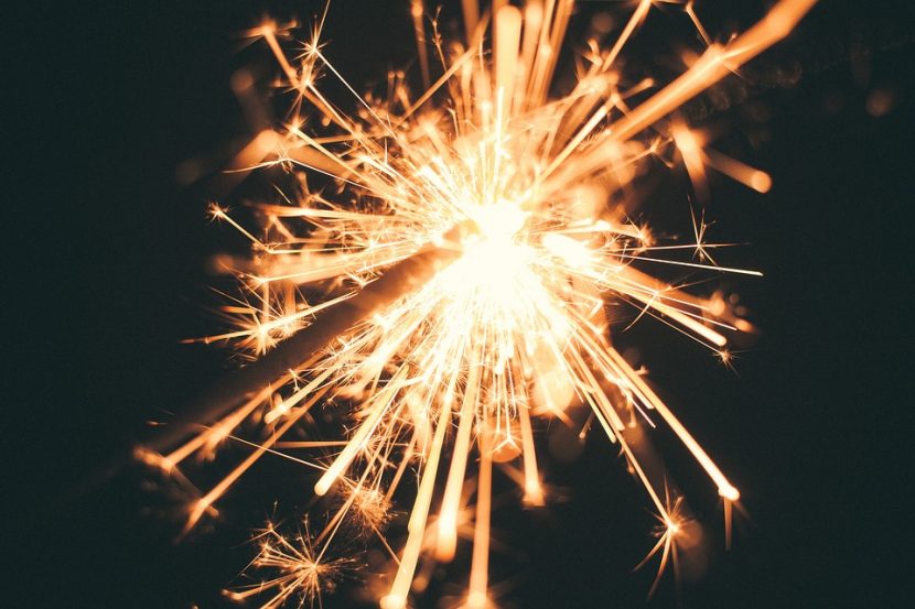 A close up shot of a lit sparkler against a black background.