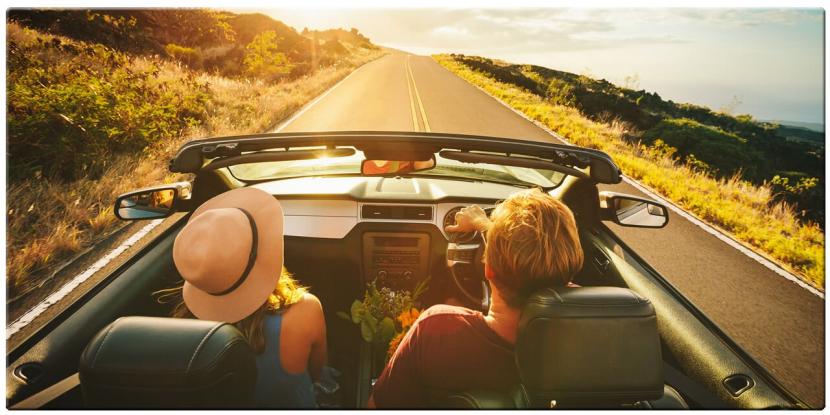 young couple driving down the road on a sunny day