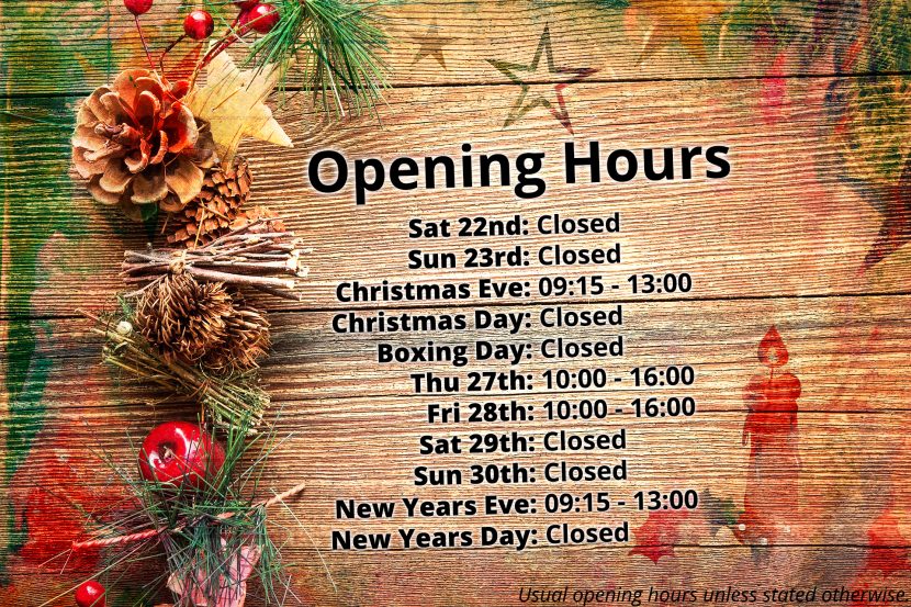 A wooden tabletop, adorned with festive oddities, with colour stained images and the opening hours imprinted upon it.